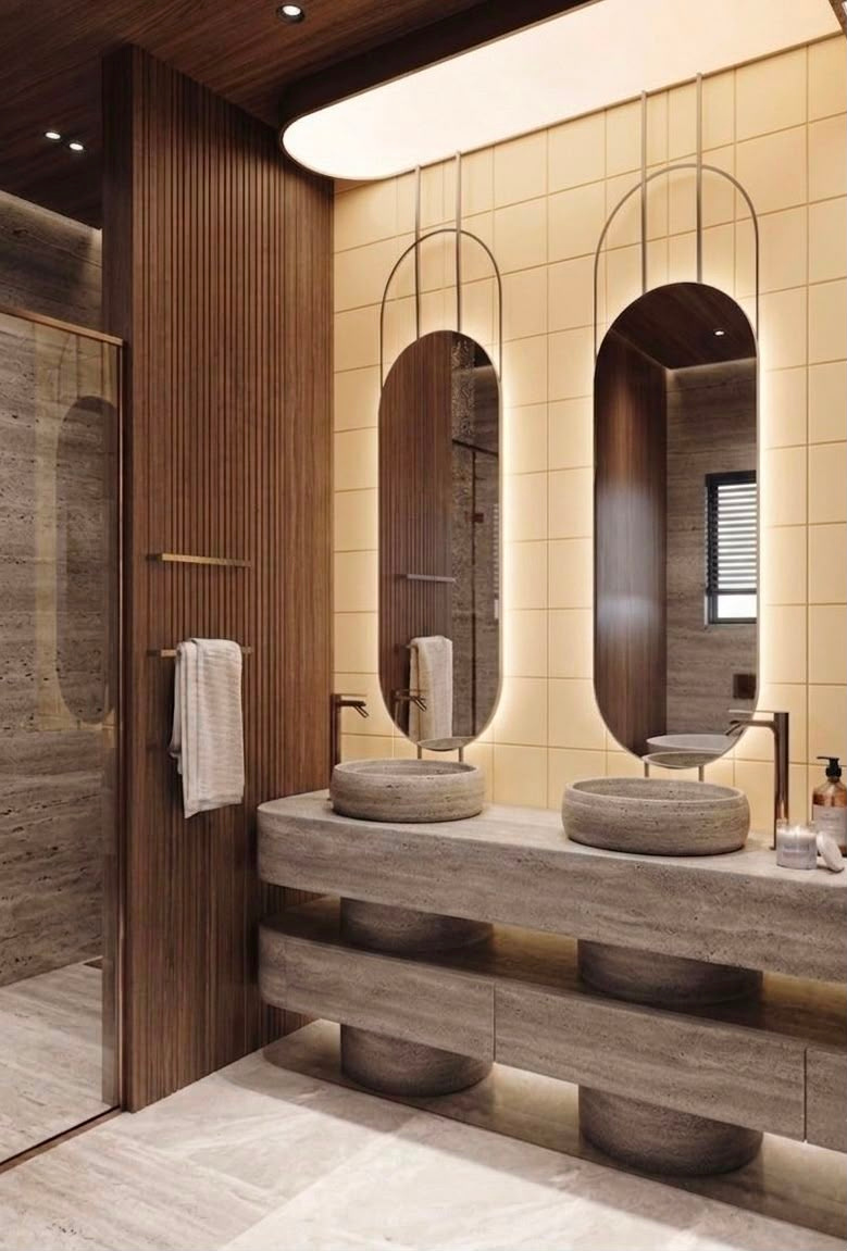 Alabaster residential bathroom interior design in Dubai with double stone vanity, arched mirrors, timber detailing and glass shower