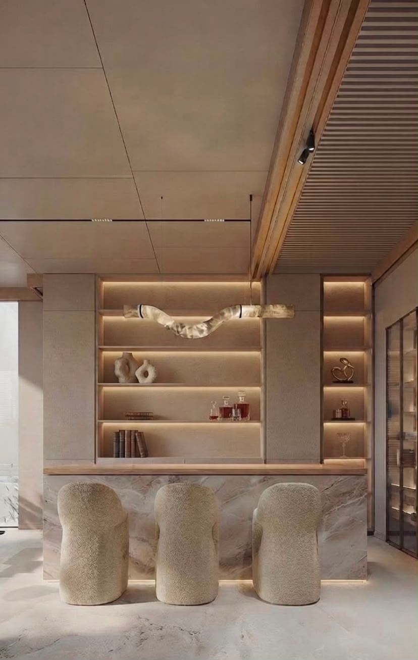 Opus residential home bar interior in Dubai with natural stone counter, three sculptural chairs, illuminated shelving and warm architectural detailing